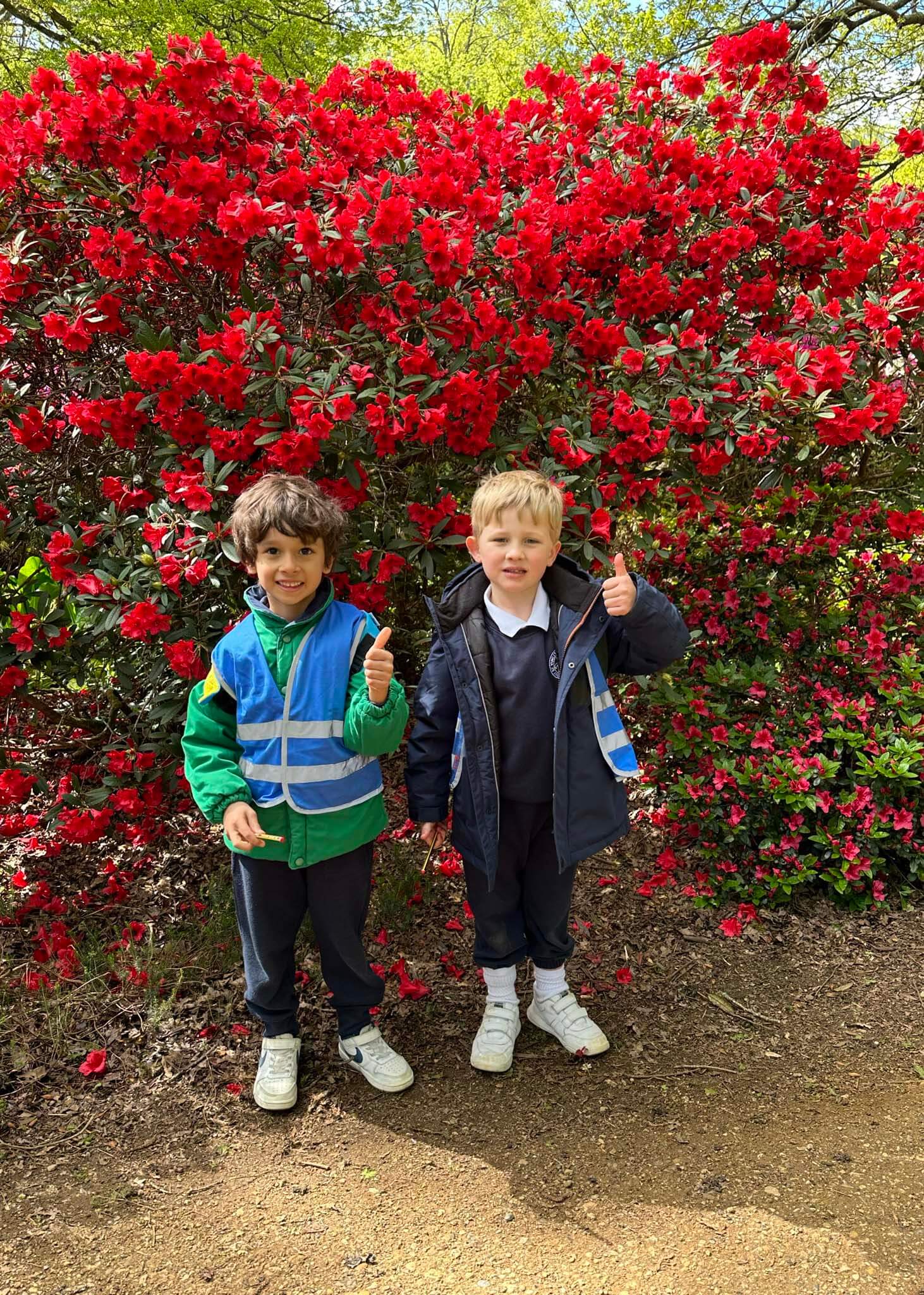 Kindergarten pupils posing in front of flower bush | Ibstock Place School, a private school near Richmond, Barnes, Putney, Kingston, and Wandsworth.