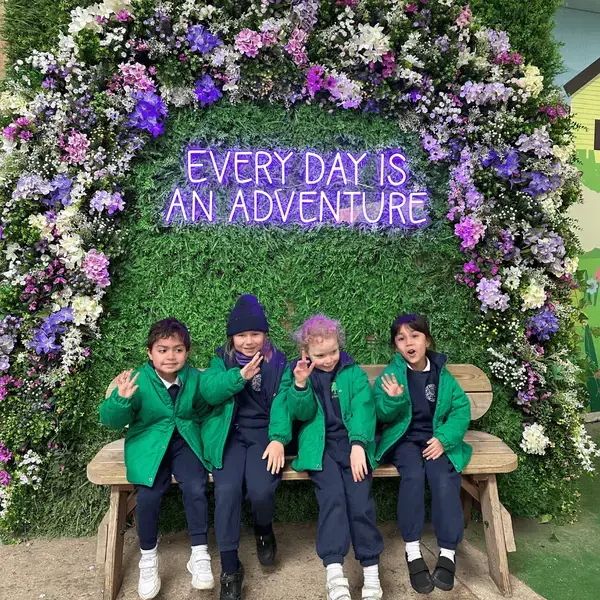 prep pupils sitting on a bench which is decorated with flowers.