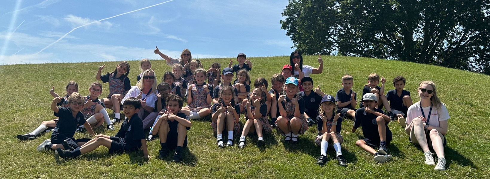 Prep pupils of Ibstock Place School, a private school near Richmond on a trip sitting on grass.